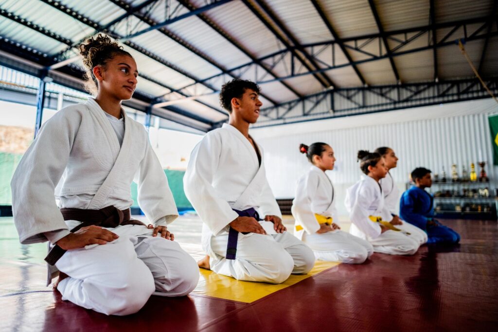 Judo athletes kneeling on a dojo